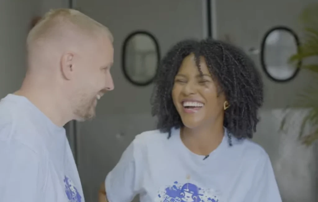 A man and a woman laughing together, wearing MATE FLOW branded shirts, representing the refreshing energy of this Medellin yerba mate soda brand.